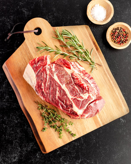 a chuck roast with herbs and spices on a cutting board
