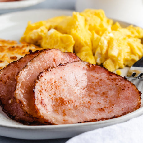 three slices of fried canadian bacon with eggs