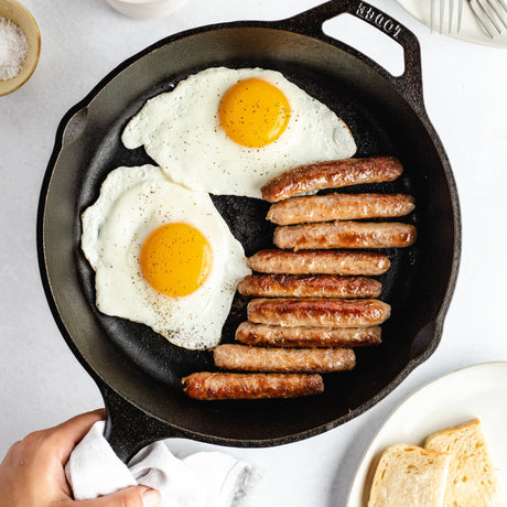 sausage links with eggs in a cast iron pan