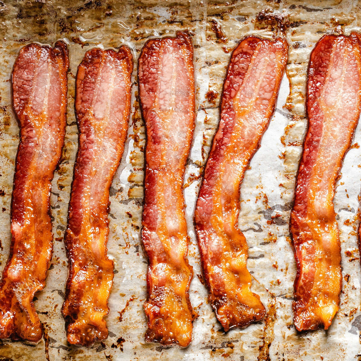 bacon frying on a baking pan