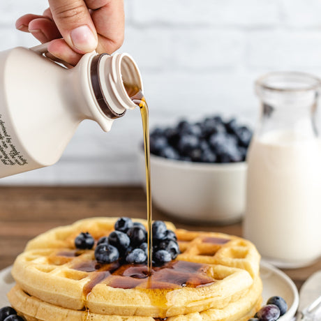maple syrup being poured over waffles