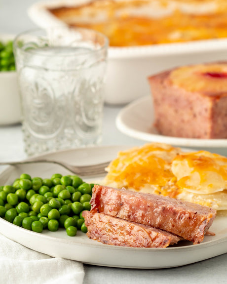 Hamloaf on a plate with peas and potatoes