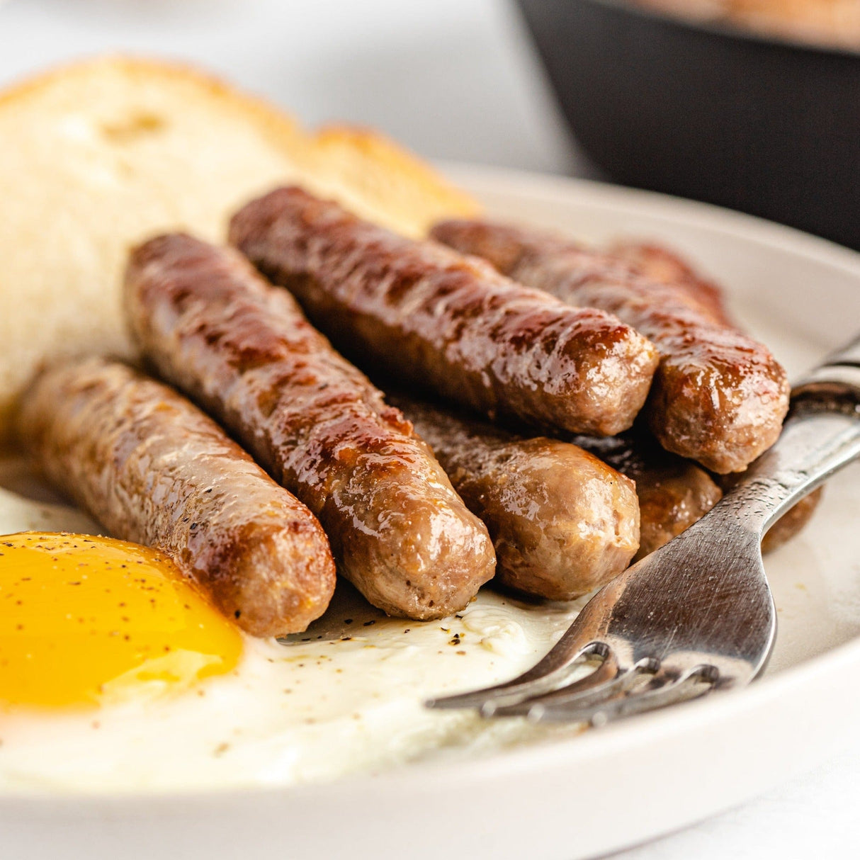 fried sausage links on a plate with eggs and toast