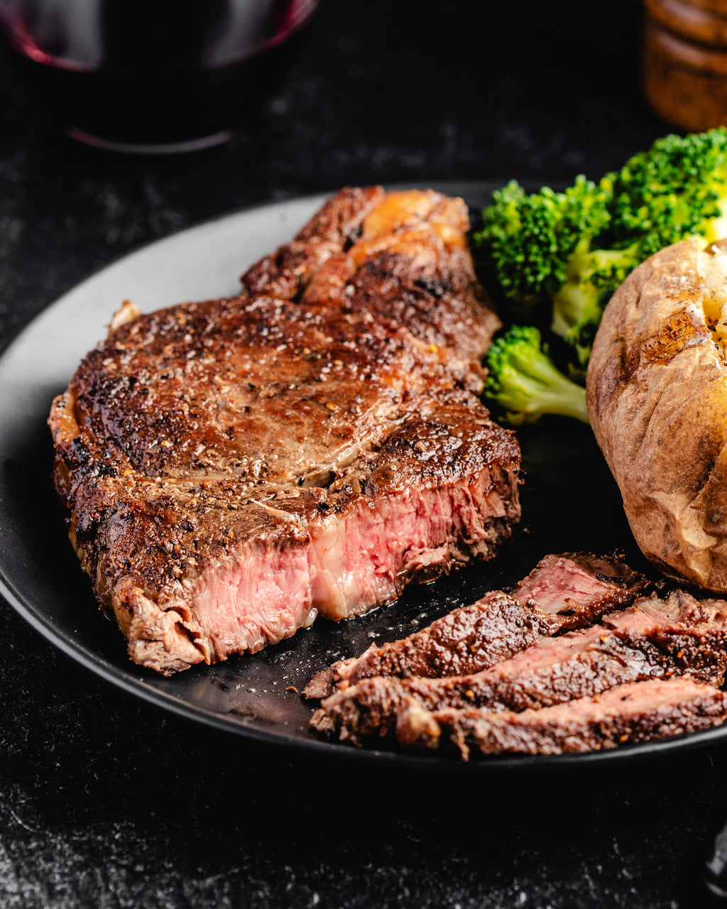 a sliced ribeye steak with vegetables and potato