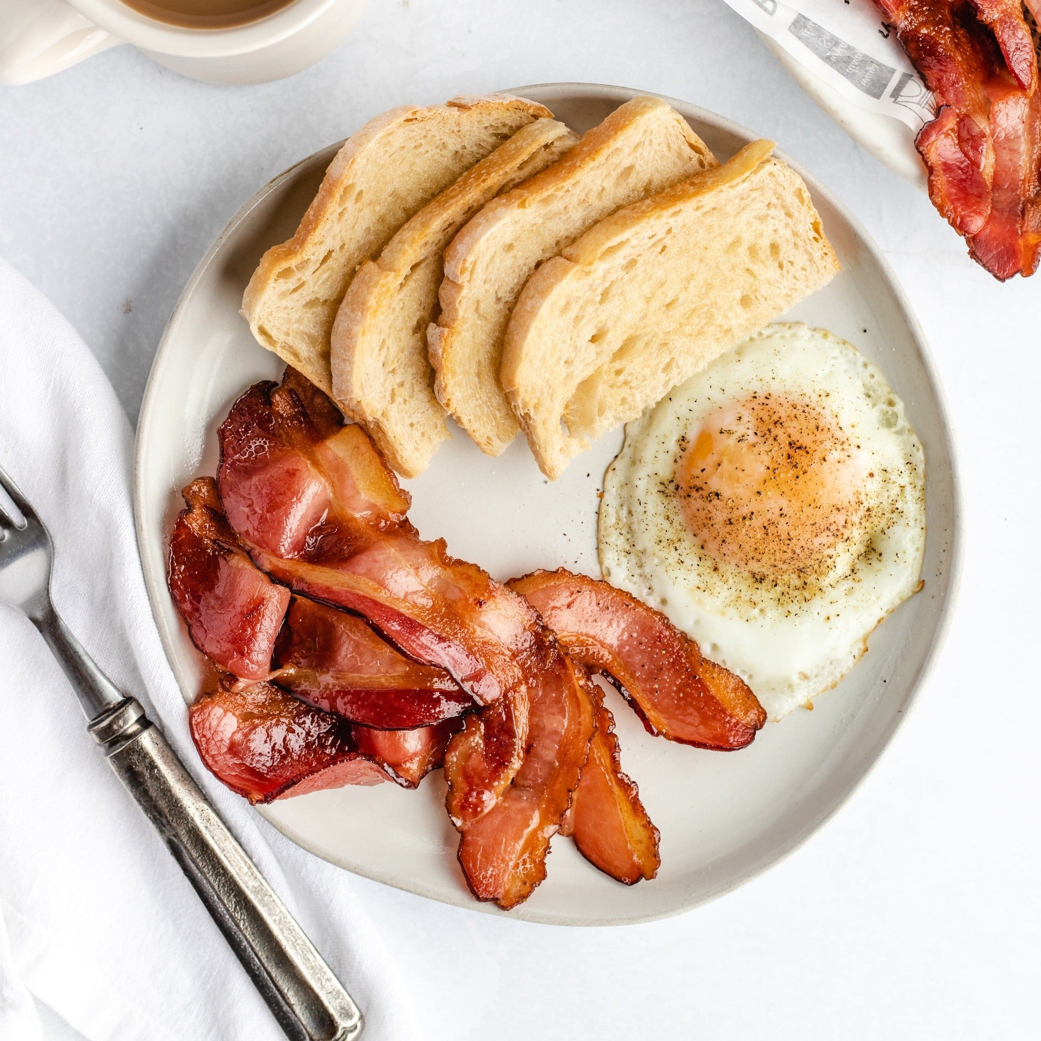 fried bacon on a plate with eggs and toast