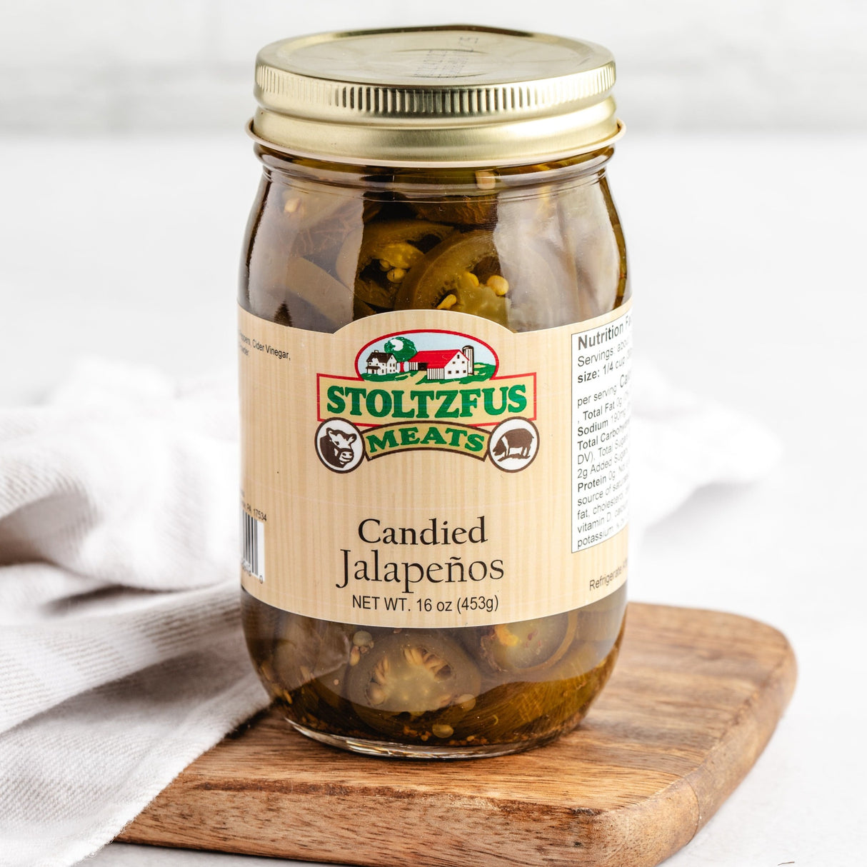 a jar of candied jalapenos on a cutting board