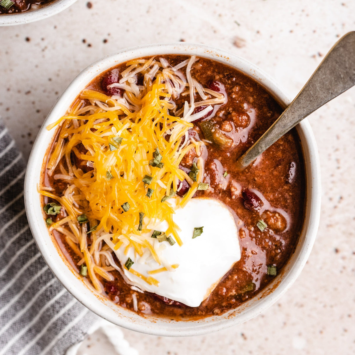 a bowl of chili with shredded cheese and sour cream